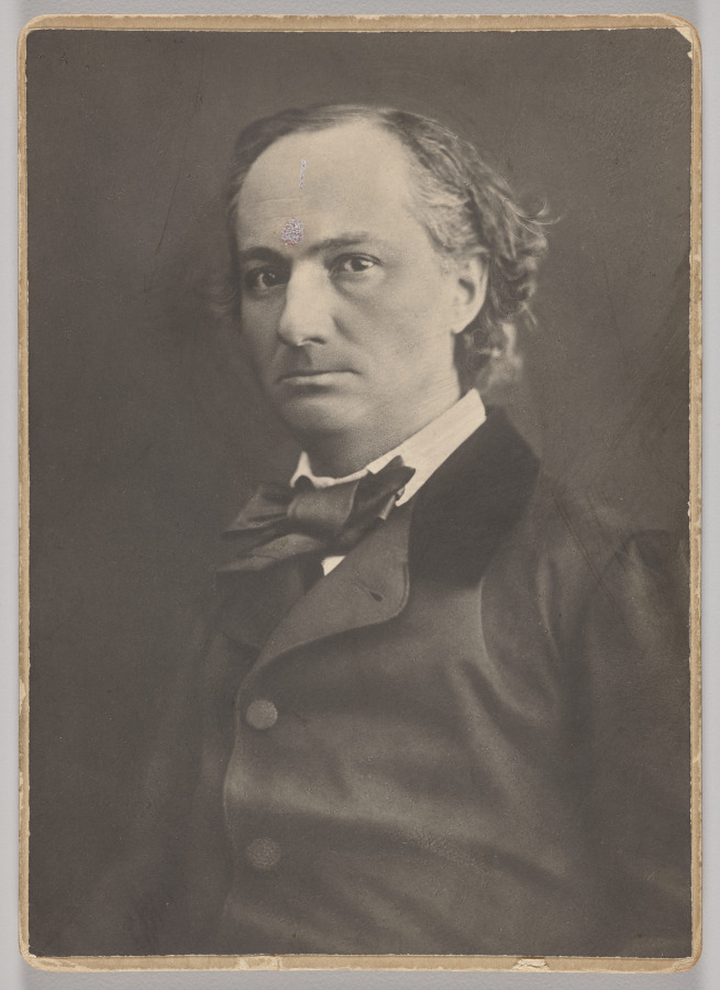 Charles Baudelaire appears from the chest up in a dark coat and bow tie, looking towards the viewer; the photograph and worn cabinet-card edges remain visible.