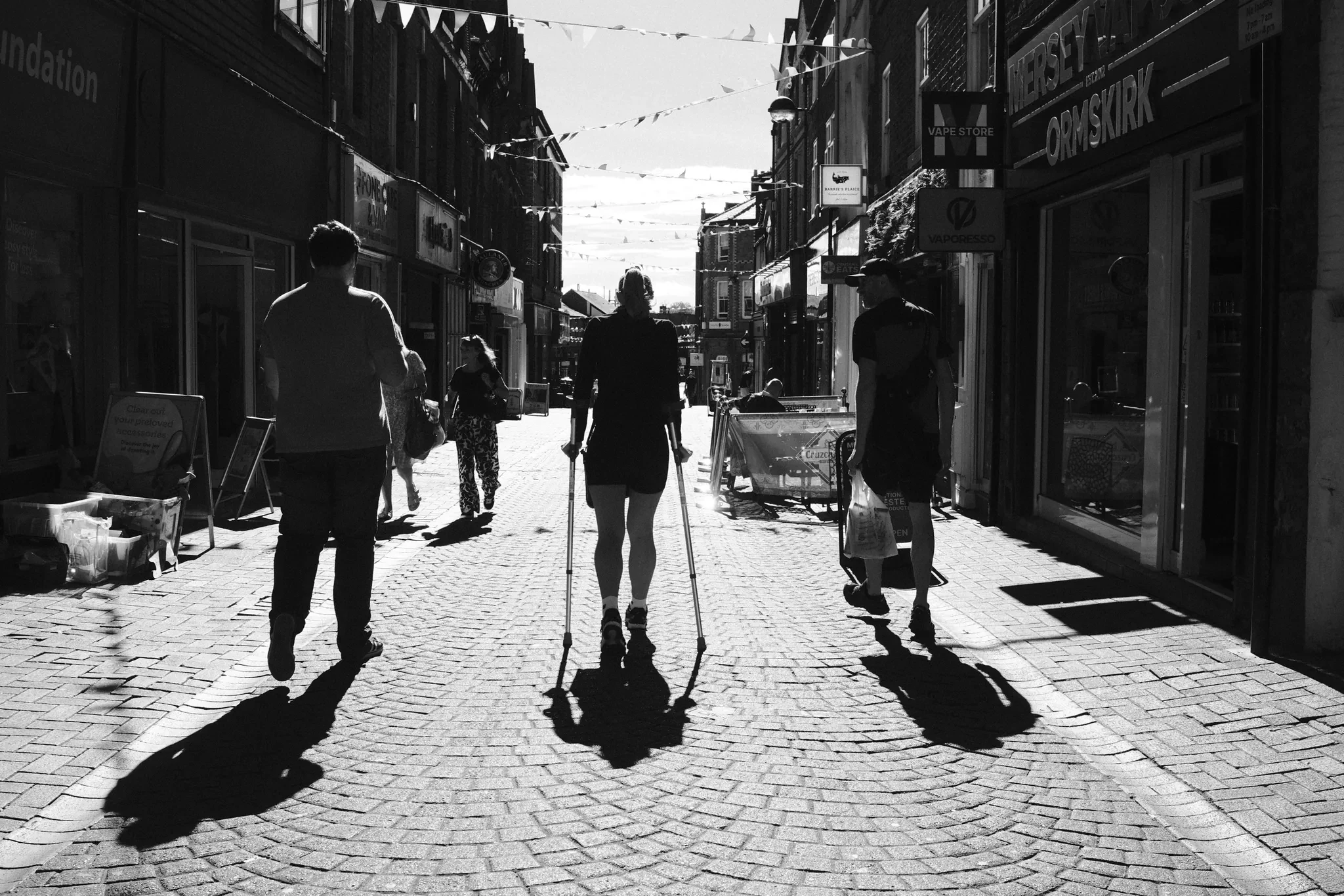Pedestrians cast long shadows along Burscough Street towards Ormskirk Clock Tower. Black and white photograph by Mark C Grant.