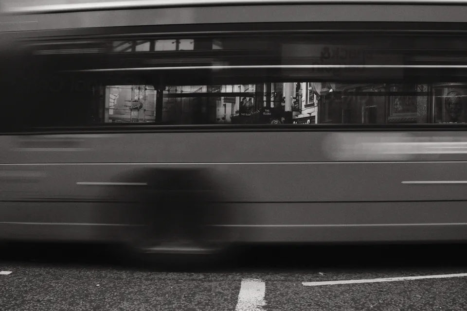 A passing bus becomes a band of motion across the street. Black and white photograph by Mark C Grant.