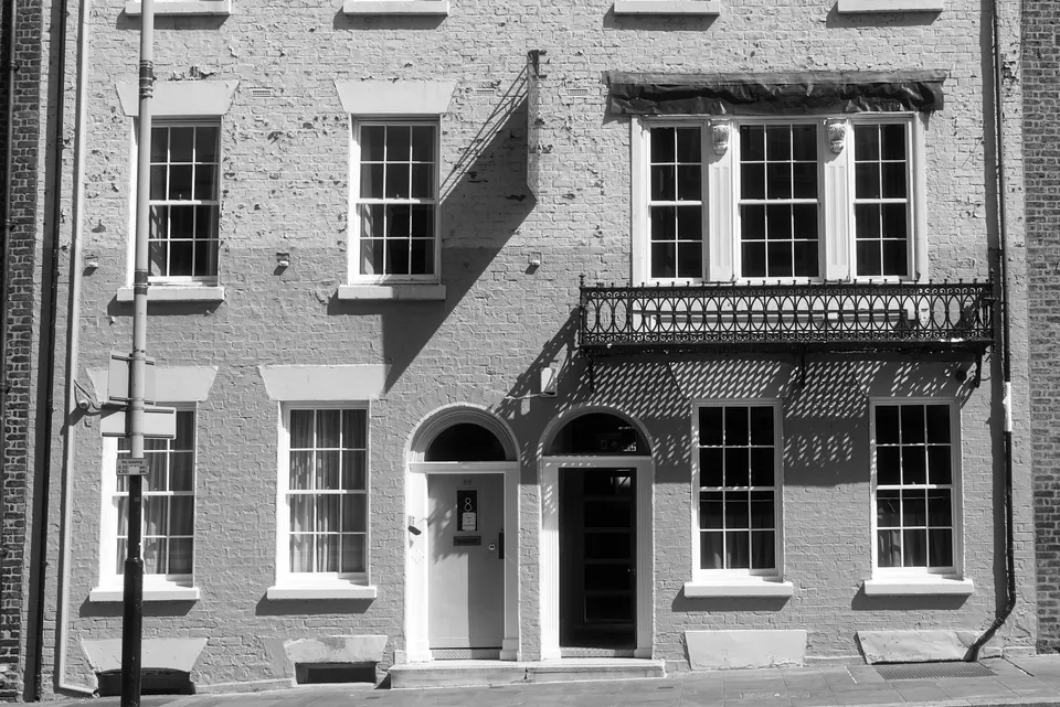 A brick facade with sash windows and a recessed doorway, in black and white. Black and white photograph by Mark C Grant.