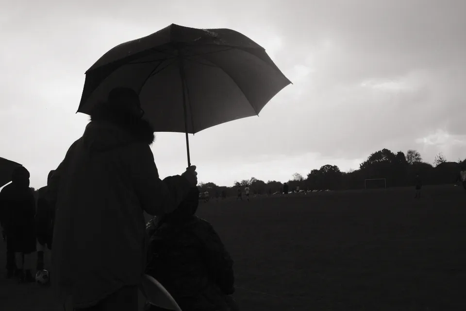 An umbrella and its holder form a dark silhouette against an overcast sky. Black and white photograph by Mark C Grant.